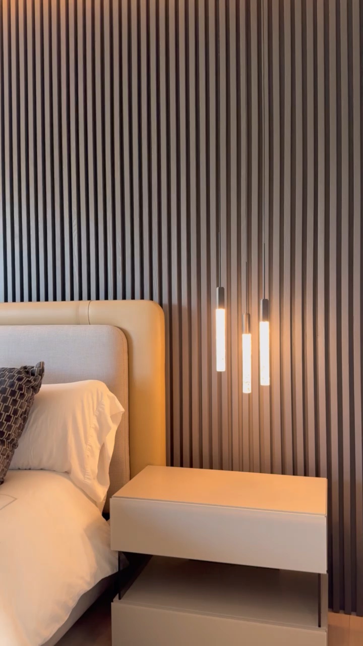 Warm bedside pendant lights glowing against a slat wall in a wind-down evening bedroom scene