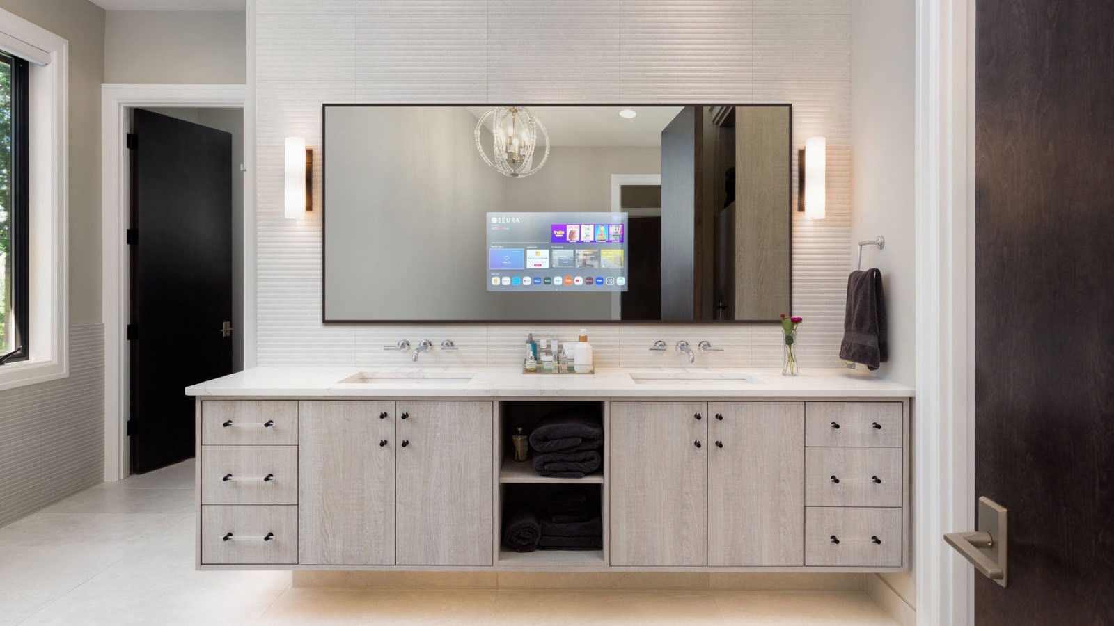 A Séura Vanity TV Mirror above a double vanity, screen showing through the glass