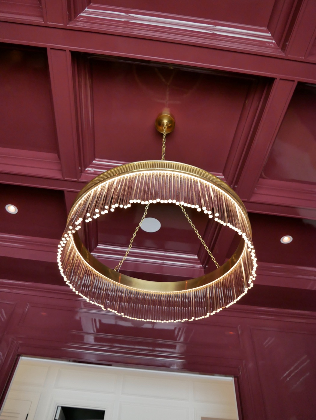 Illuminated chandelier centered beneath a glossy coffered ceiling