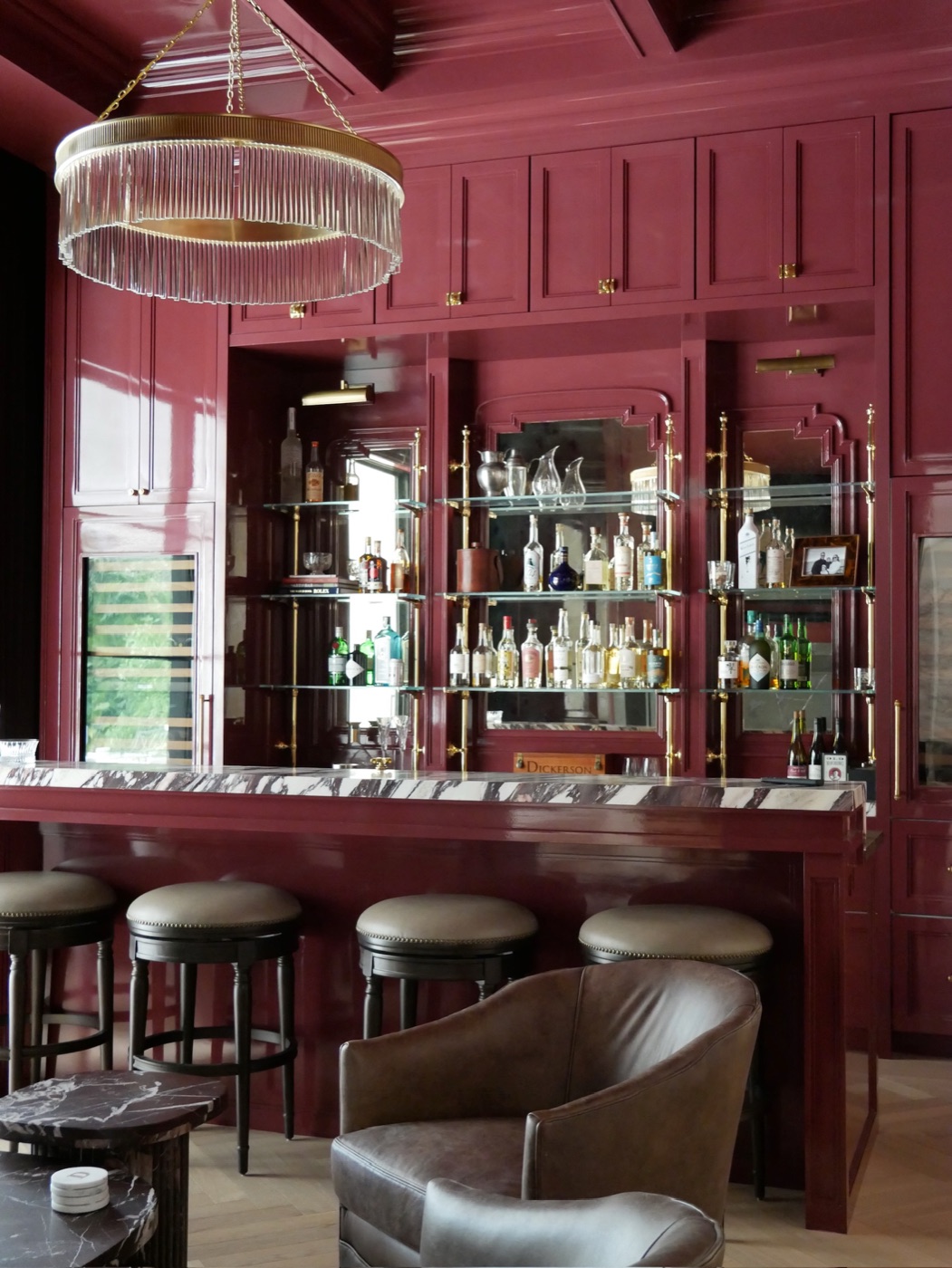 Lacquered home bar with brass and glass shelving, marble counter and concealed wine storage